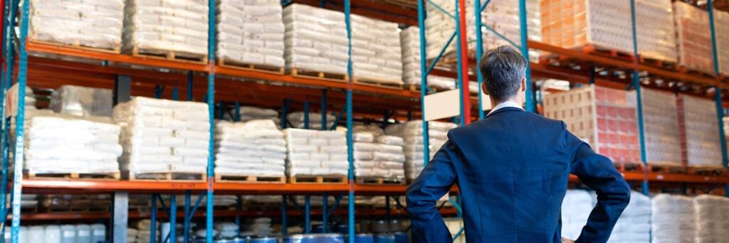 Dirigeant observant un entrepôt de marchandises illustrant la valeur des stocks / Business executive observing a warehouse full of goods, symbolizing stock value